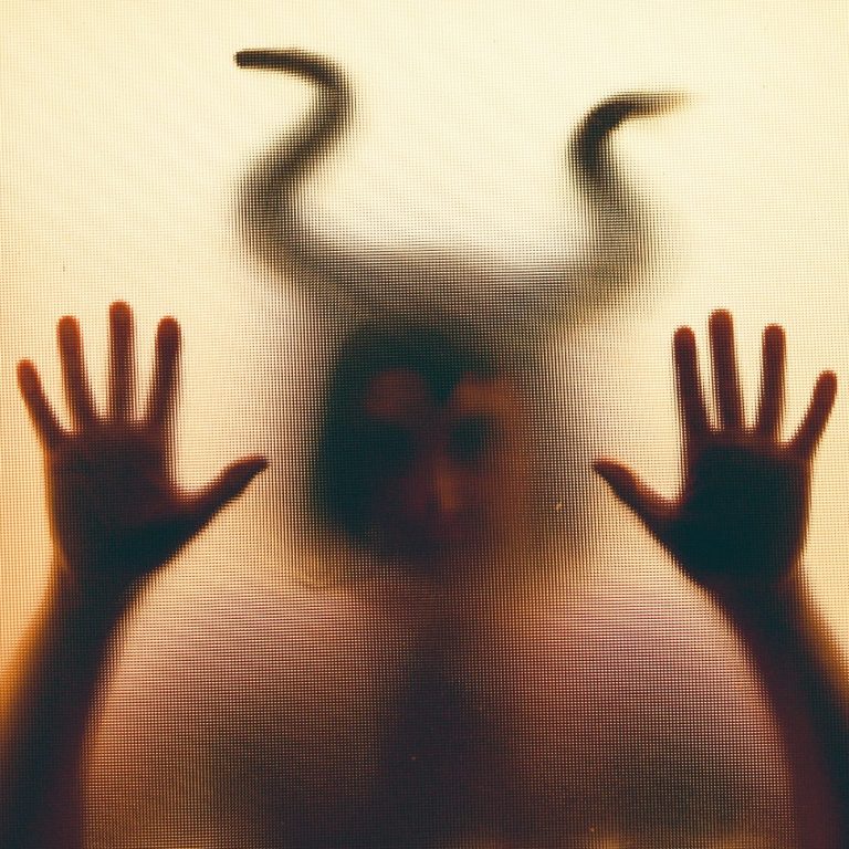 Figura sombría observando desde una ventana, representando el ego que se impone y se aísla del resto.